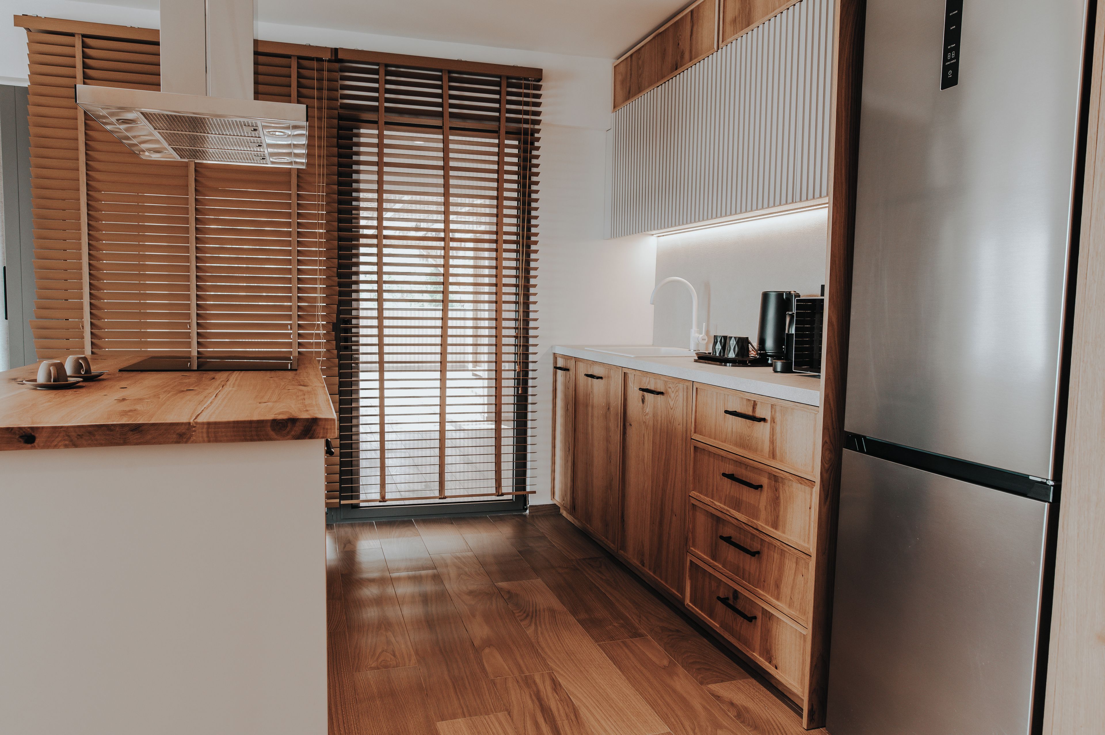Eine moderne Küche mit Holzschränken, einem Edelstahlkühlschrank und einem Einbauofen.