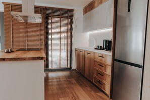Eine moderne Küche mit Holzschränken, einem Edelstahlkühlschrank und einem Einbauofen.
