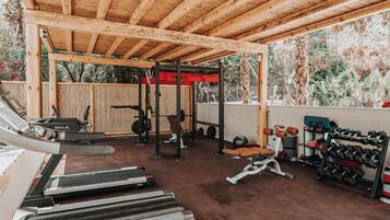 A covered gym area with treadmills, weight benches, and a squat rack.