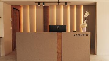 A reception desk with a laptop, a nameplate reading 'SAGREDO,' and a vertical light panel.