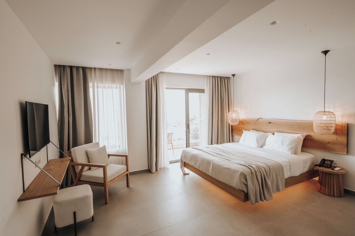 Una habitación de hotel moderna con cama, escritorio, silla, televisor y balcón.
