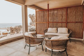A balcony with wicker furniture, a view of the beach, and a bamboo wall. - Sagredo Boutique Hotel And Spa (Kos)