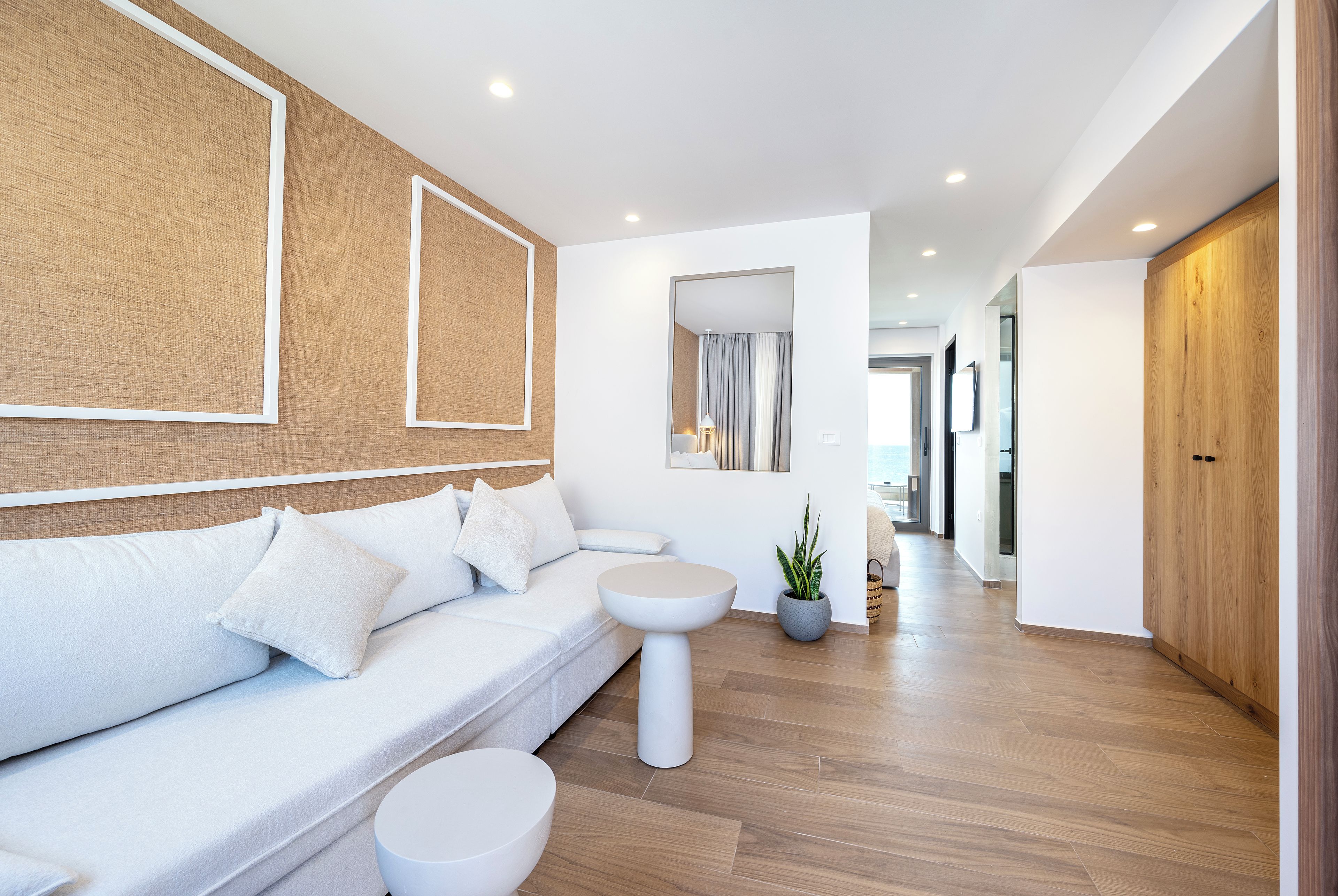 Un salon moderne avec un canapé blanc, une table basse ronde et une plante en pot.