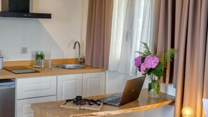 A modern kitchen with a laptop on the counter, a sink, and a window with curtains.