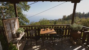 A wooden deck with a table and chairs, surrounded by a wooden railing, overlooking a scenic landscape.