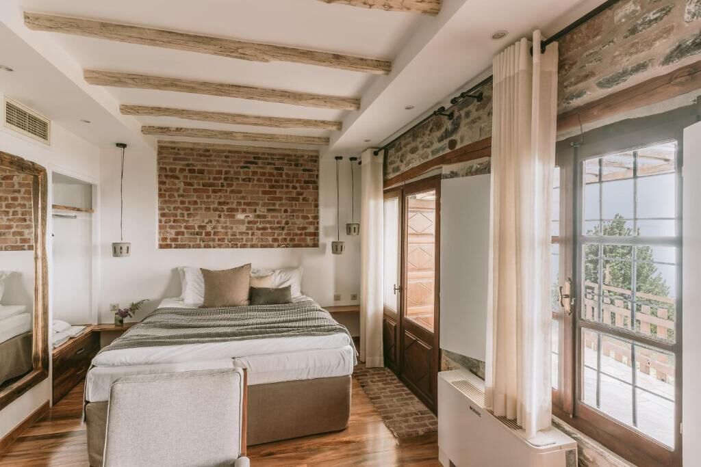 Une chambre avec un mur en briques, un lit, une fenêtre et un radiateur.