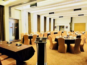 A conference room with tables and chairs, a podium, and a door with a sign.