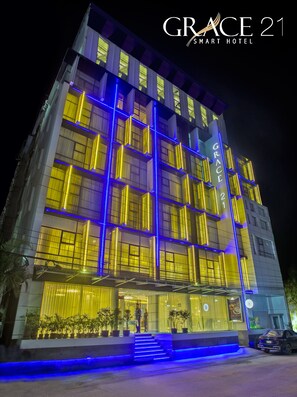 A multi-story hotel with illuminated vertical lines and a prominent entrance with steps.