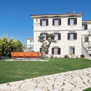 A multi-story building with a symmetrical facade, a central entrance, and a staircase leading to the upper floors. - Bi Salkım Perla Otel (Bozcaada)