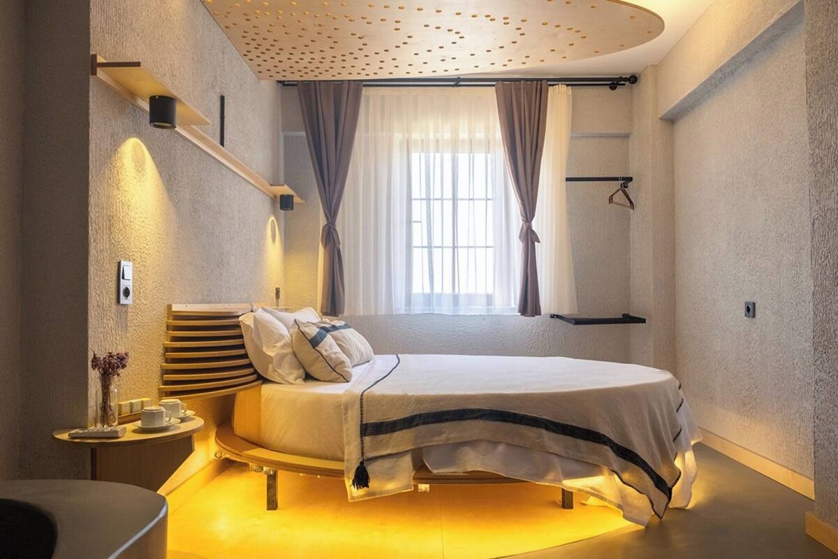 Ein modernes Schlafzimmer mit Bett, Nachttisch und einem Fenster mit Vorhängen.