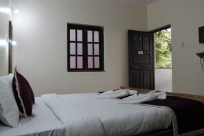 A bedroom with a bed, a window with a view, and a door. - My Sea Side Budget Stay (Calangute)