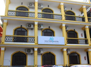 Un hotel de varios pisos con balcones, unidades de aire acondicionado y un cartel que indica que es el HOTEL SEA SIDE.
