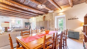 A dining area with a wooden table and chairs, a stone wall, and a view of greenery outside. - Awesome home in Collazzone (Collazzone)
