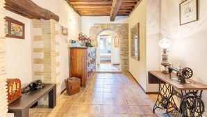 A hallway with exposed wooden beams, stone walls, a vintage sewing machine, and a telephone. - Awesome home in Collazzone (Collazzone)