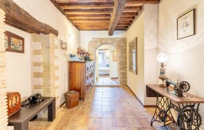 A hallway with exposed wooden beams, stone walls, a vintage sewing machine, and a telephone. - Awesome home in Collazzone (Collazzone)