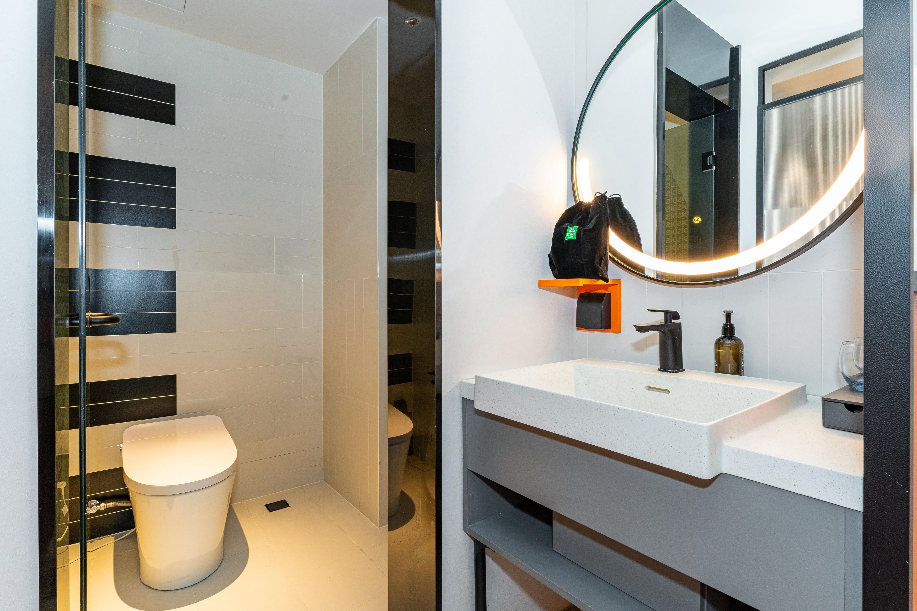Un baño moderno con inodoro, lavabo y espejo.