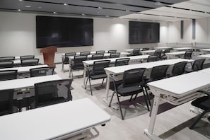 A conference room with white tables, black chairs, a podium, and a large projection screen. - Ibis Xian Bell Tower Huimin Street (Xi'an)