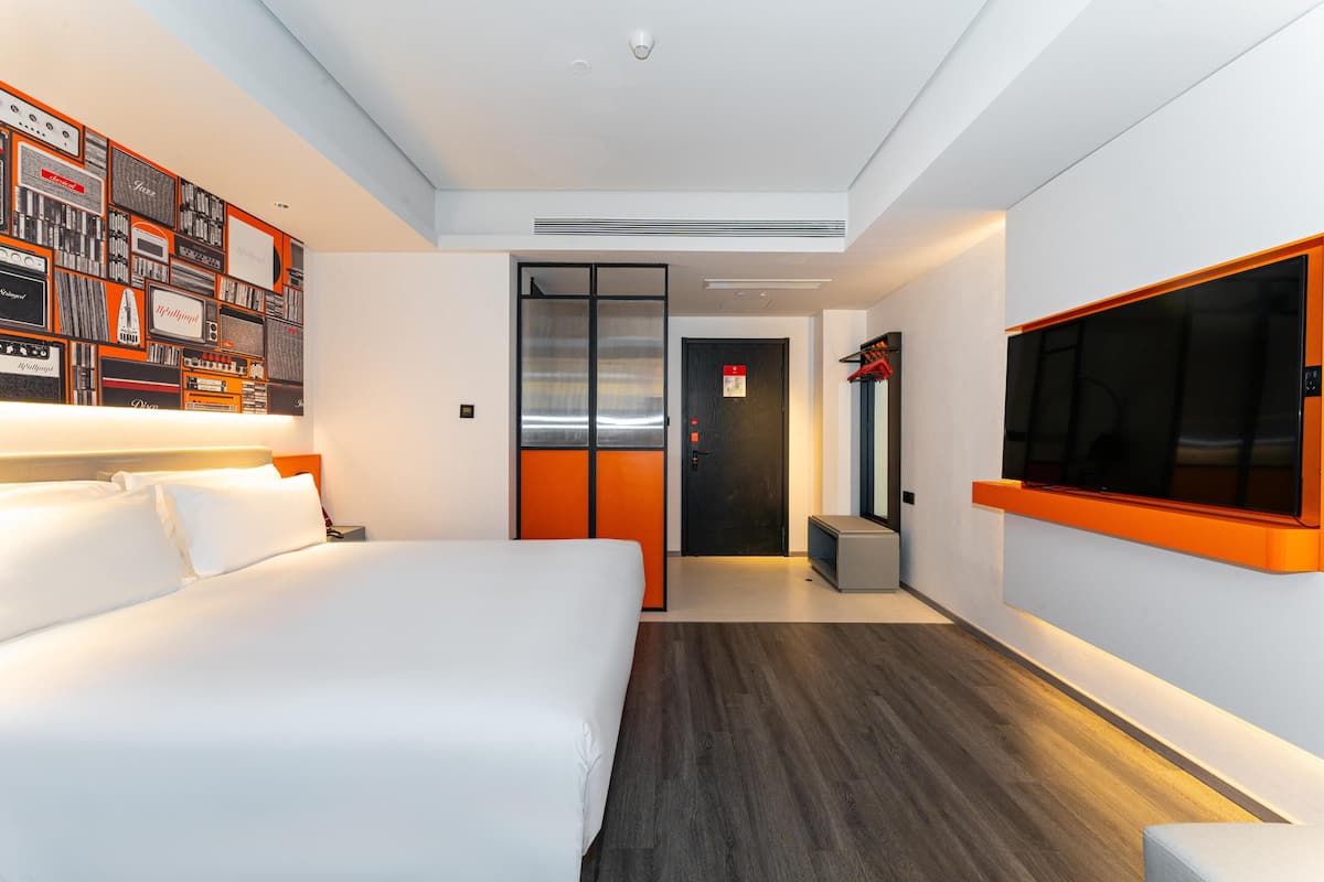 A modern hotel room with a large bed, a TV mounted on the wall, and a unique wall decoration.