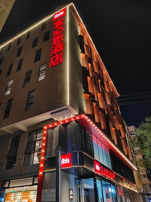 A hotel with a prominent 'ibis' sign, a modern facade with geometric patterns, and a well-lit entrance. - Ibis Xian Bell Tower Huimin Street (Xi'an)
