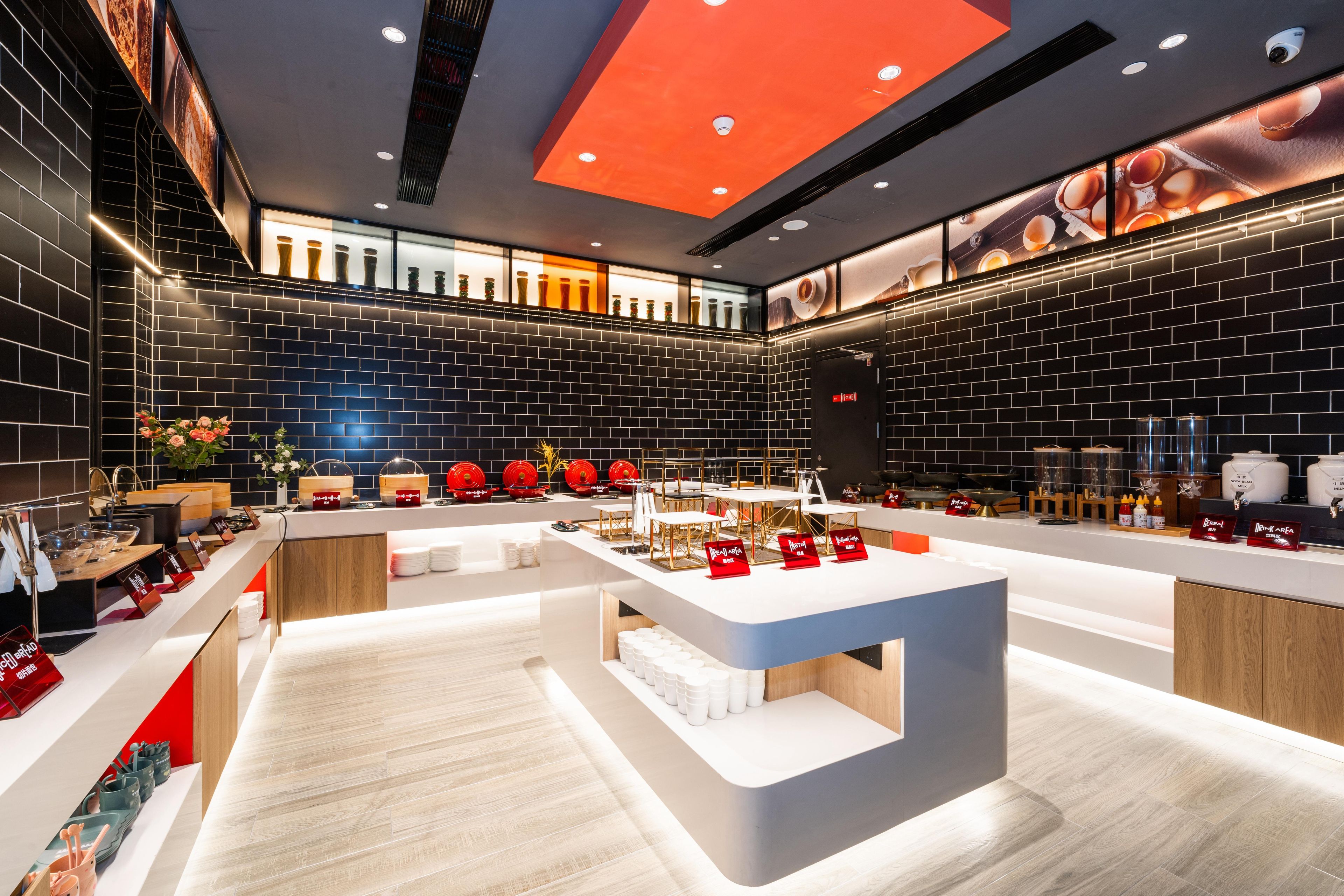 Un interior de restaurante moderno con una barra central, paredes de ladrillo negro e iluminación empotrada en el techo.