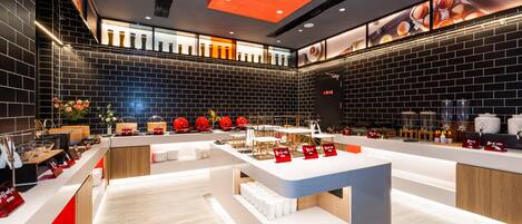 A modern restaurant interior with a central counter, black brick walls, and a ceiling with recessed lighting.