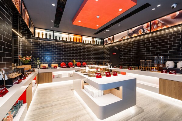 Interior modern d'un restaurant amb un taulell central, parets de maó negre i un sostre amb il·luminació empotrada.