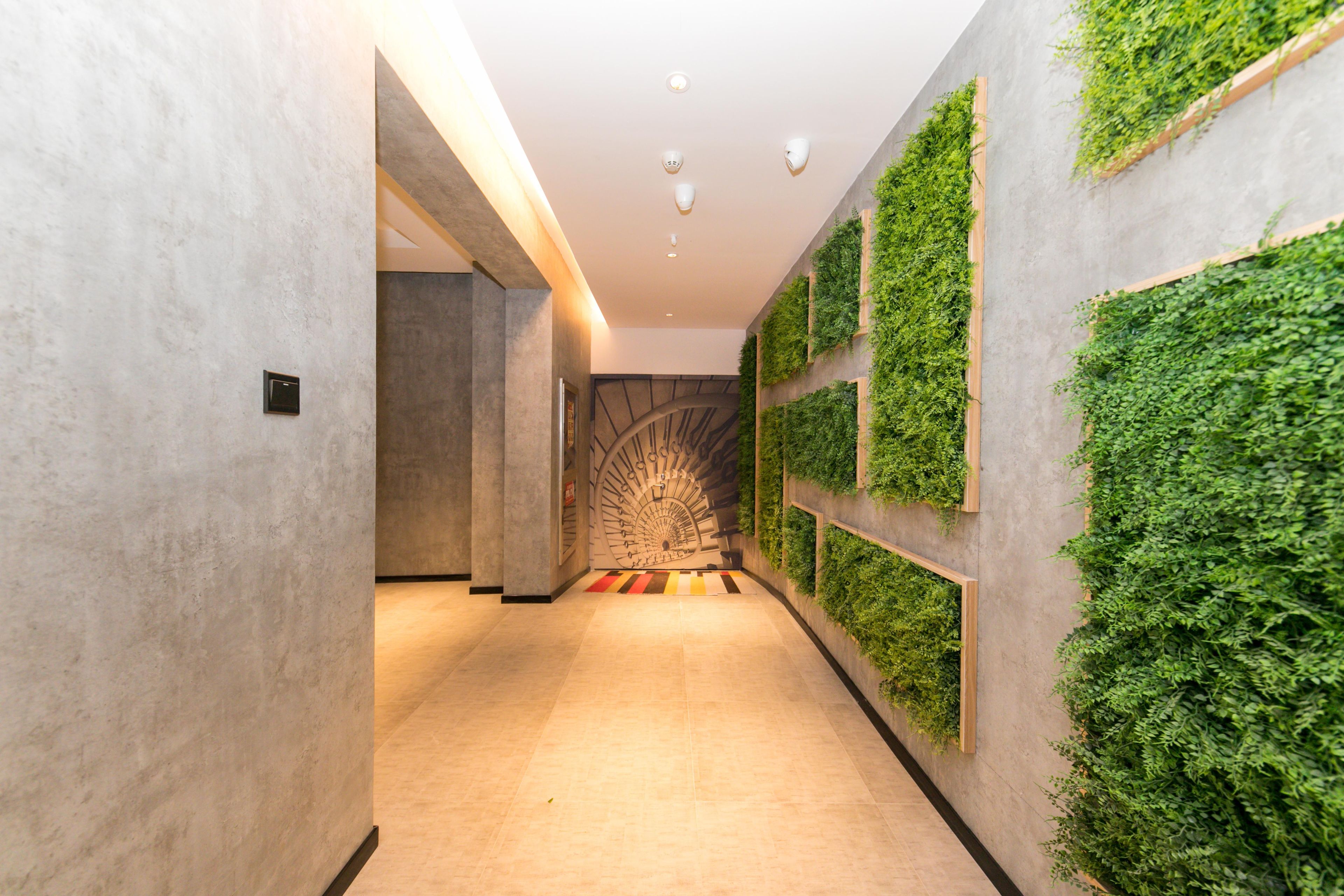 A hallway with a modern design, featuring a spiral staircase and vertical garden walls.