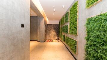 A hallway with a modern design, featuring a spiral staircase and vertical garden walls.