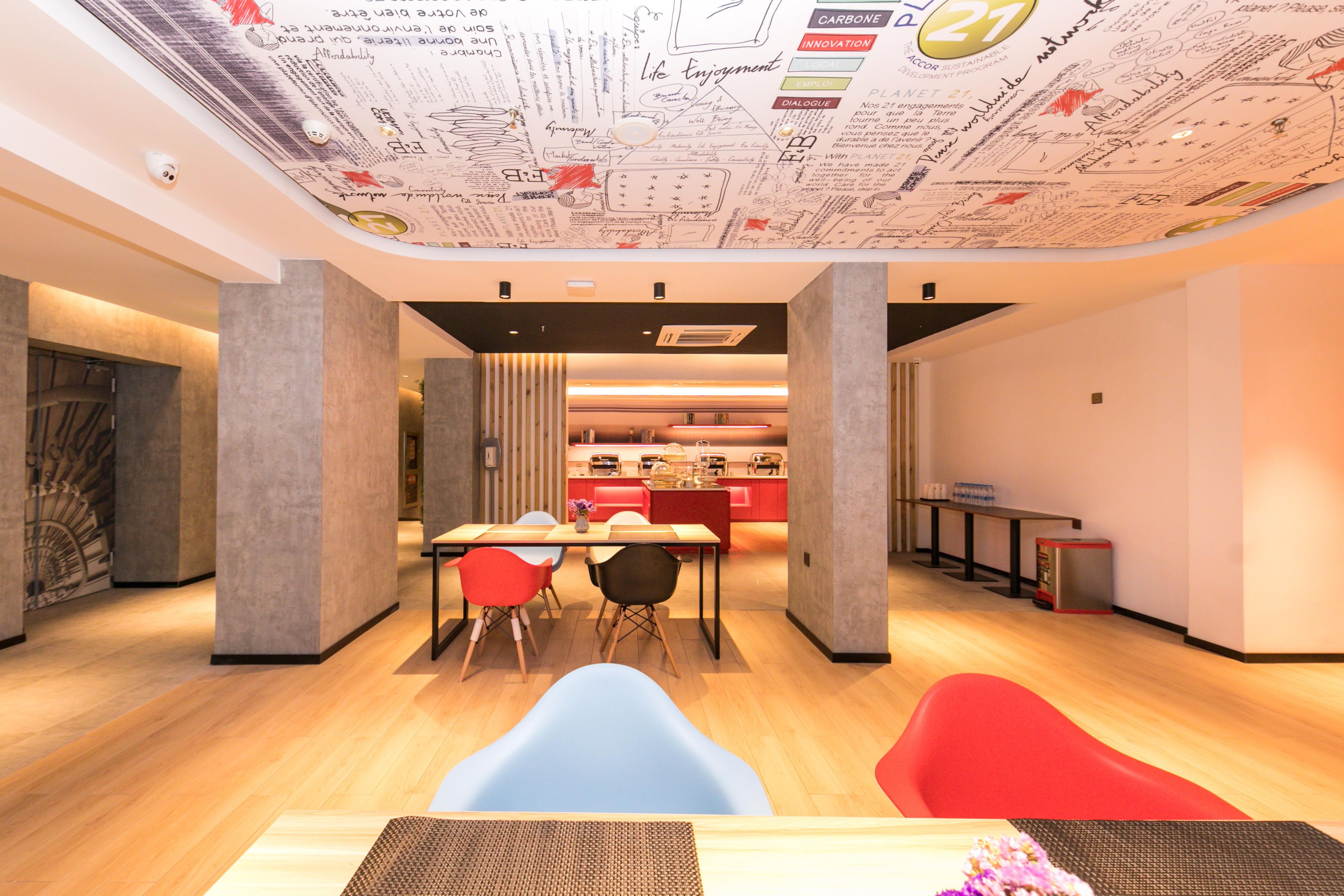 A modern interior with a dining area, kitchen, and a ceiling with architectural drawings.
