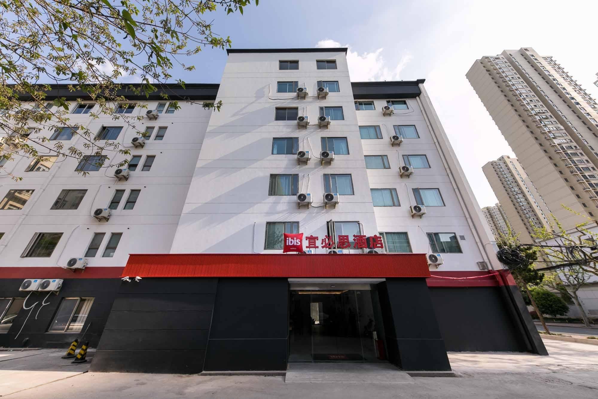 A multi-story hotel with a red awning, air conditioning units, and a clear sky.