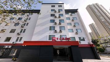 A multi-story hotel with a red awning, air conditioning units, and a clear sky.
