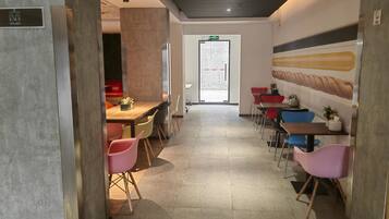 A modern interior with a long dining area, colorful chairs, and a large wall mural.