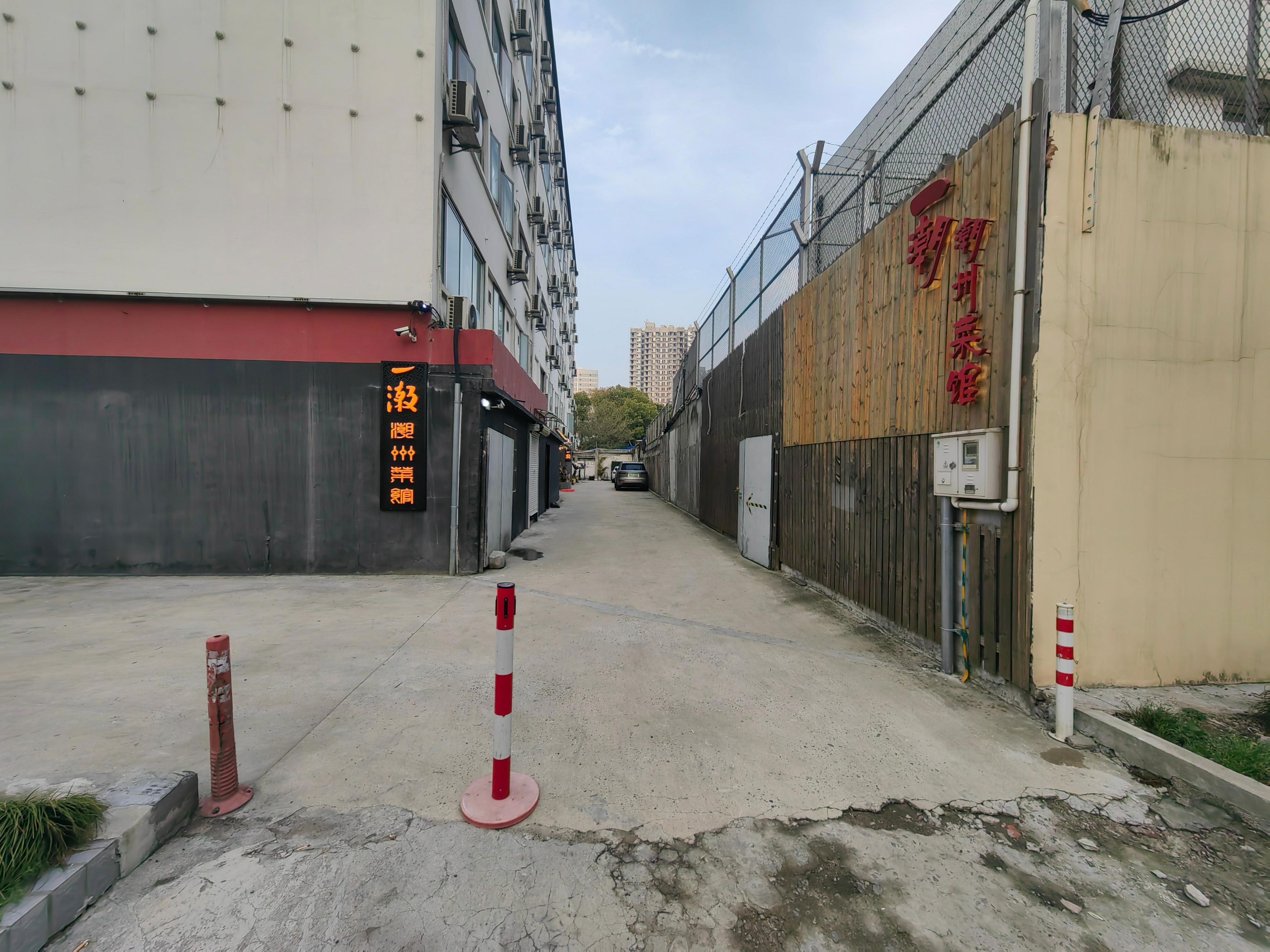 A narrow urban street with a building featuring a red awning and a sign with Chinese characters.