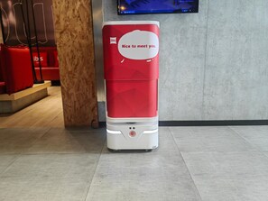 Quiosc autoatenció vermell i blanc amb el missatge 'Nice to meet you' al vestíbul d'un hotel.