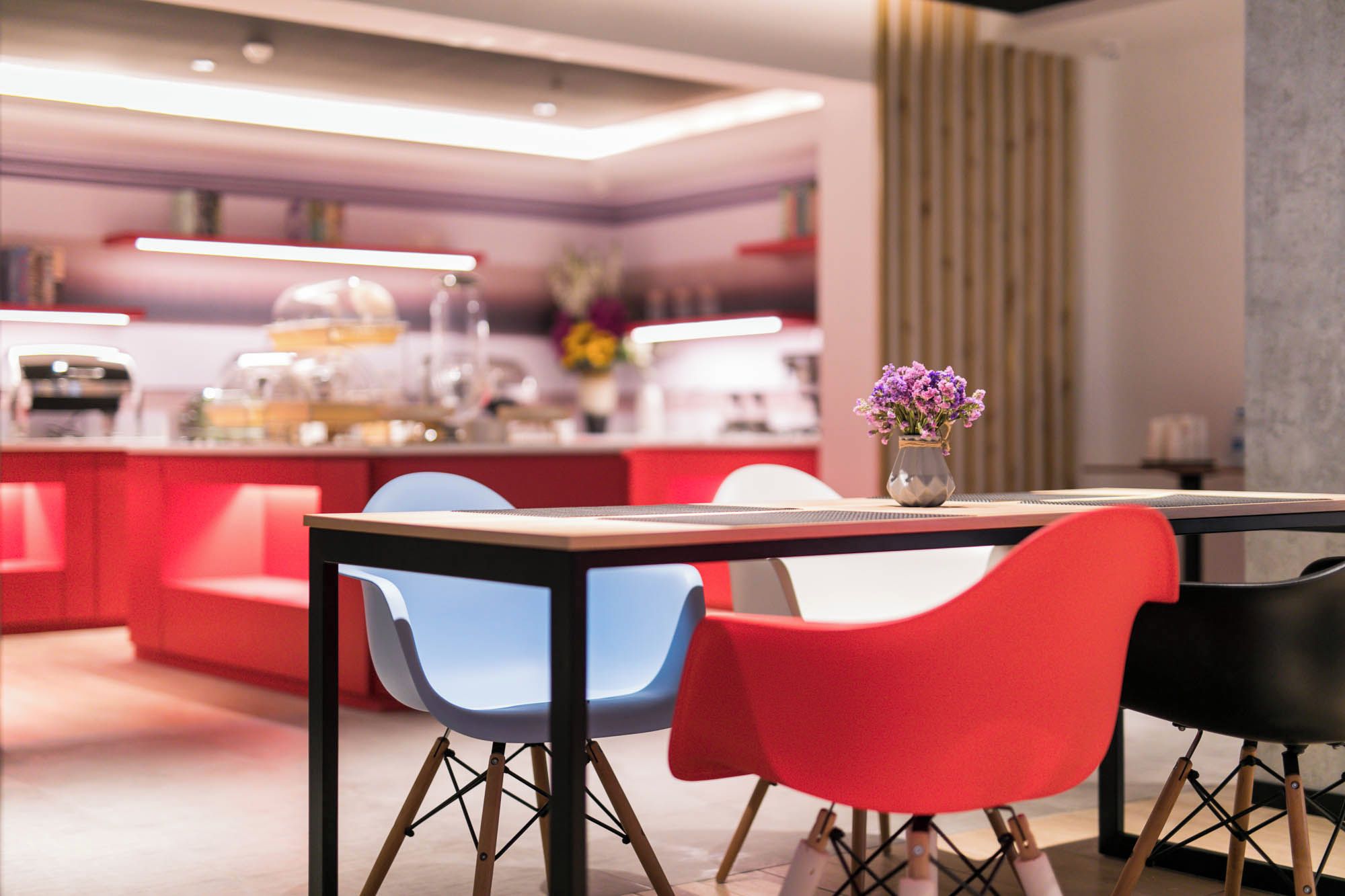 A modern dining area with a table, chairs, and a vase of flowers.