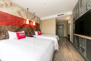 A hotel room with two beds, a TV, and a hallway leading to a door. - Ibis Hotel (Shanghai)