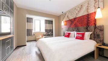 A hotel room with a large bed, a desk, a chair, a window with curtains, and a wall with a clock and abstract design.
