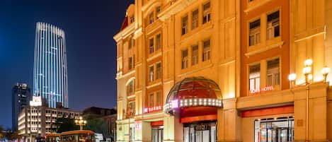 A hotel with a prominent dome entrance, a red awning, and a sign reading 'IBIS HOTEL.'