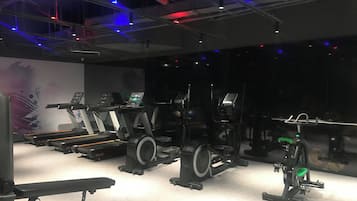 Un gimnasio con cintas de correr, bicicletas estáticas y máquinas de pesas.