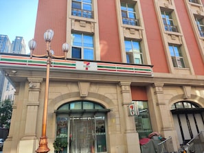 A 7-Eleven convenience store with a large sign, a coffee shop, and a staircase leading to an entrance. - Ibis Hotel Tianjin Railway Station Jinwan Plaza (Tianjin)