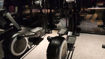 Una bicicleta estática con pantalla digital, un apilador de pesas y un pedal.
