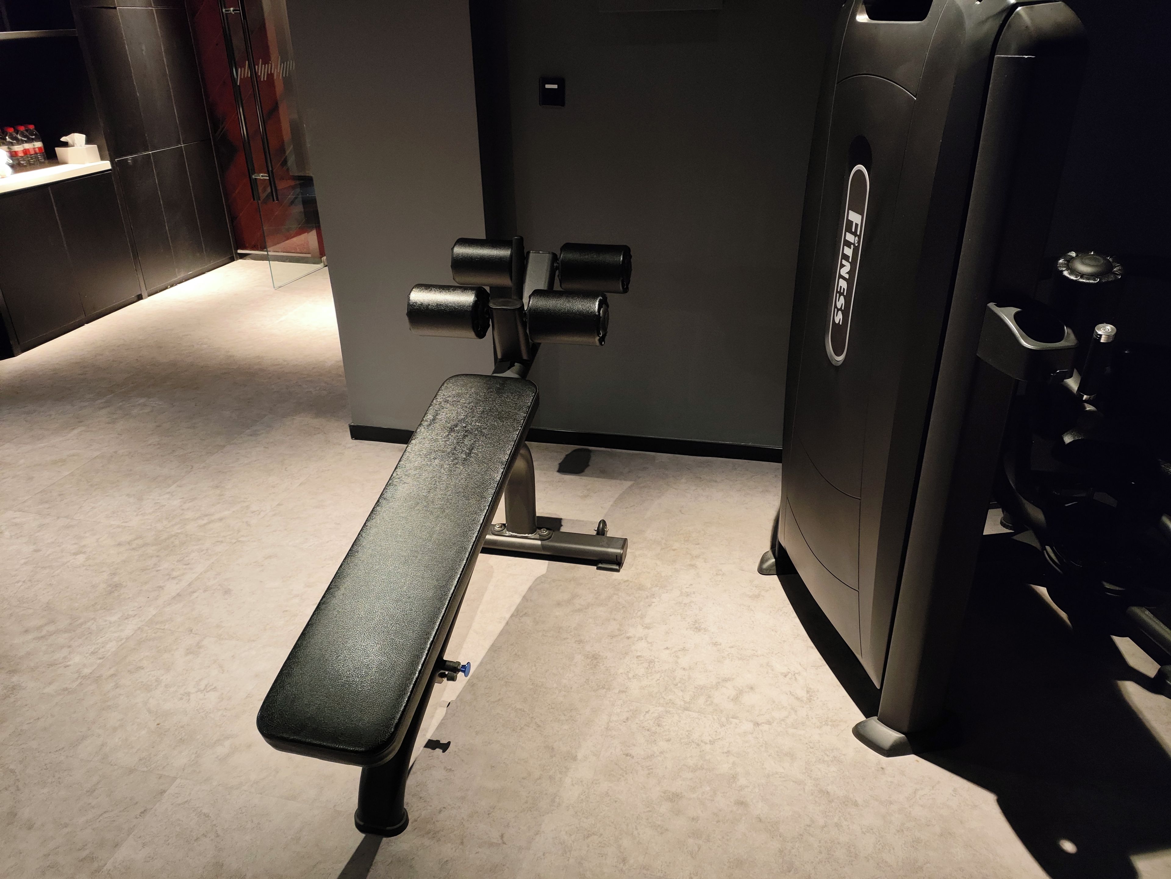 Une salle de sport équipée d’un banc de développé couché et d’une pile de poids.