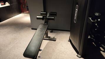 Ein Fitnessraum mit Langhantelbank und Gewichtsblock.