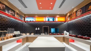 A modern kitchen with a long counter, black tiled walls, and red accents. - Ibis Hotel Tianjin Railway Station Jinwan Plaza (Tianjin)