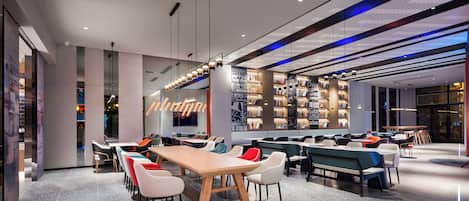 A modern restaurant with a long wooden table, multiple seating areas, and a wall with motivational quotes.