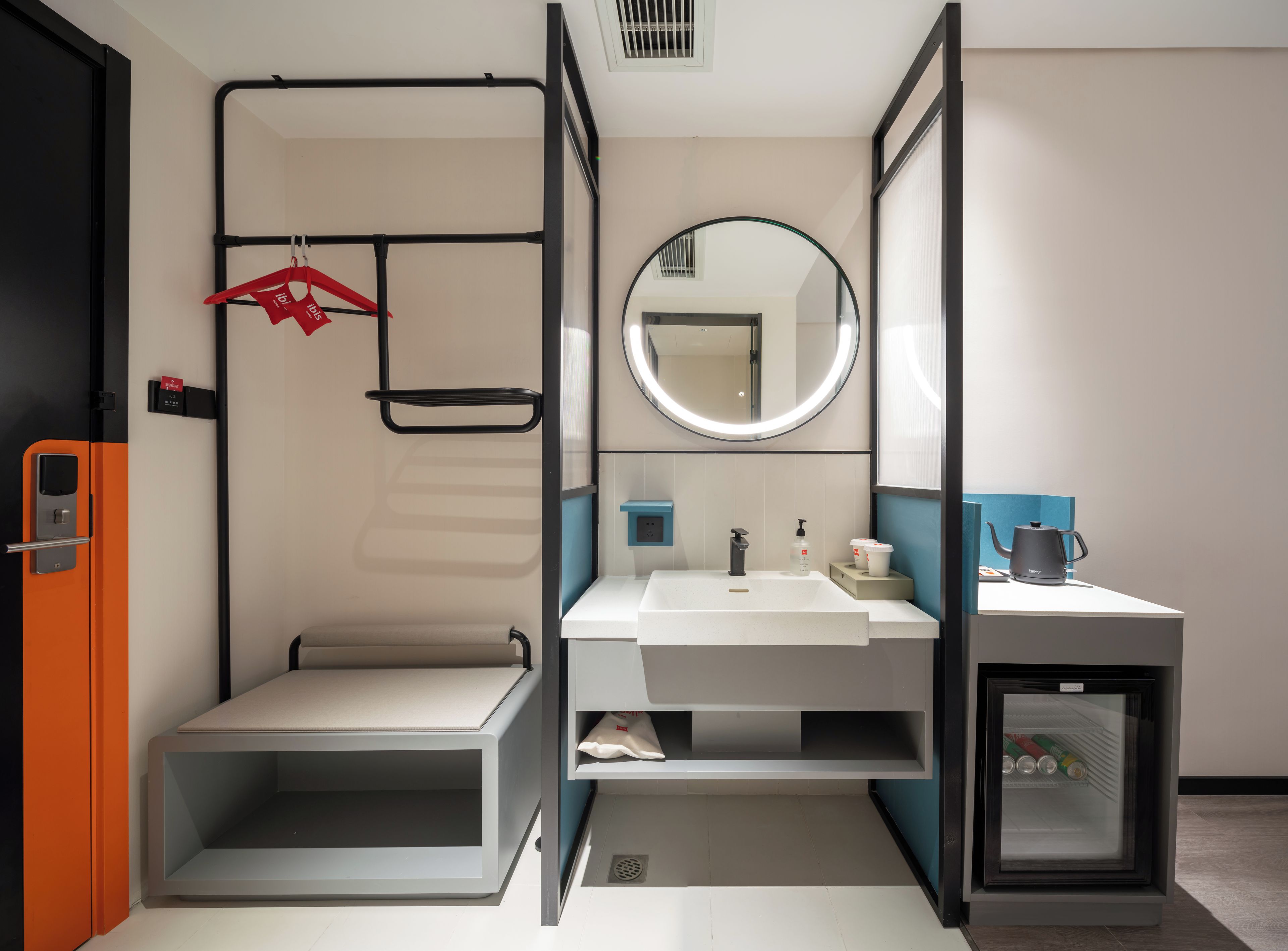 Ein modernes Badezimmer mit Waschbecken, Spiegel, Handtuchhalter und einem kleinen Schrank mit einem Wasserkocher.
