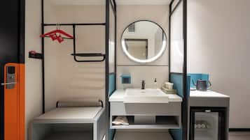 Ein modernes Badezimmer mit Waschbecken, Spiegel, Handtuchhalter und einem kleinen Schrank mit einem Wasserkocher.