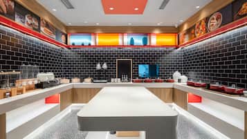 A modern kitchen with a long counter, black tiled walls, and red accents.
