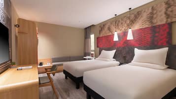 Habitación de hotel con dos camas, un escritorio, una silla, un televisor y un cuadro abstracto grande en la pared.