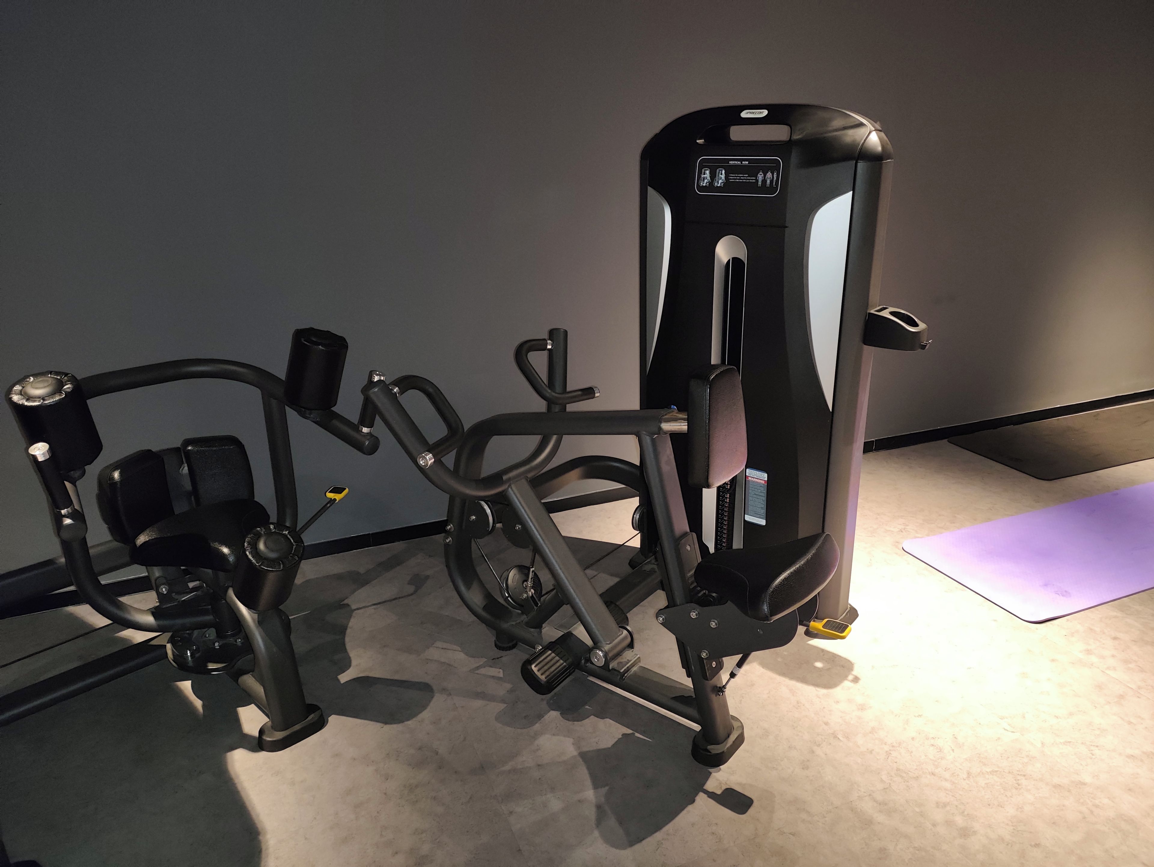 Une salle de sport équipée de matériel d’exercice, notamment une machine pour les exercices de développé couché et une machine pour les exercices de presse à cuisses.